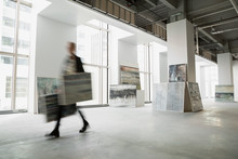 Art Dealer Walking With Paintings In Art Gallery