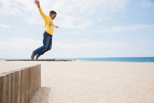 Boy Jumping From Beach Wall