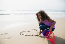 Girl Drawing Heart-shape In Sand On Beach