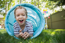 Portrait Smiling Boy Inside Toy Tunnel In Backyard
