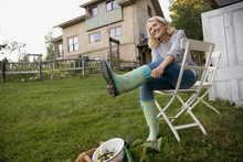Smiling Woman Putting On Wellies In Garden
