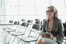 Businesswoman With Digital Tablet Sitting On Chair In Meeting Room