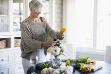 Woman Arranging Flowers And Drinking Wine