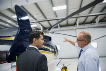 Pilot And Manager Discussing Helicopter In Airplane Hangar
