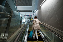 Woman Ascending Escalator At Train Station