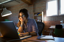 Female Designer Using Laptop At Desk In Office