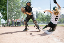 Middle School Girl Softball Player Sliding Into Home Base Next To Catcher