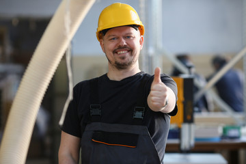 Smiling worker in yellow helmet show confirm sign with thumb up at arm portrait. Manual job DIY inspiration joinery startup idea fix shop hard hat industrial education profession career concept