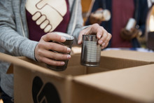 Volunteer Packing Tin Cans Into Cardboard Box