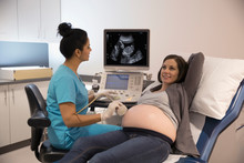 Female Nurse Performing Ultrasound On Pregnant Woman In Examination Room