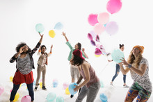 Women Friends Playing With Multicolor Balloons Against White Background