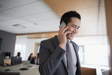 Smiling Businessman Talking On Cell Phone In Conference Room