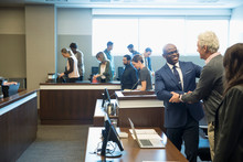 Smiling Defendant And Attorney Handshaking In Legal Trial Courtroom