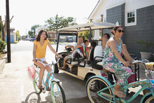 Family With Beach Cruiser Bicycles And Golf Cart In Summer Beach House Driveway