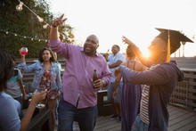African American Father And Son Celebrating Graduation On Summer Deck