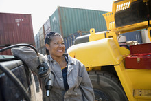 Portrait Smiling Female African American Mechanic Holding Drill, Fixing Machinery In Industrial Container Yard