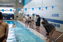 Swim Team Cheering Teammate Swimming In Swimming Pool At Competitive Swim Meet