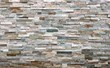 Stone cladding wall made of  striped stacked slabs of natural multicolor rocks. Panels for exterior, background and texture.