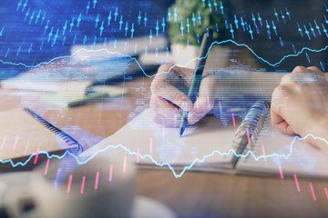 Financial forex graph drawn over hands taking notes background. Concept of research. Multi exposure