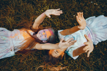 Beautiful girls with a colorful dry paints. Friends have fun in a summer park