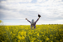 Exuberant Woman With Arms Outstretched In  Idyllic, Yellow Rapeseed Crop Field On Farm