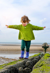 cute little girl doing balance exercises on the beach