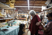 Female Fashion Designers Fitting, Pinning Fabric On Woman In Workshop