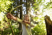 Confident Girl Aiming Bow And Arrow In Woods