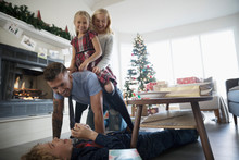 Uncle Playing With Nieces And Nephews In Christmas Living Room