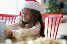 Smiling Girl Using Digital Tablet, Wearing Christmas Santa Hat