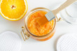 Homemade orange fruit facial mask (exfoliating sugar scrub) in the glass jar. Citrus DIY cosmetics and spa recipe. Top view, copy space.