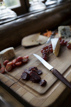 Still Life Cheese Board With Dried Salami, Tomatoes And Grapes