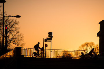 Silhouette of bikers passing on bridge silhouette by sunset