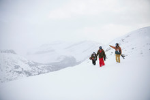 Male Snowboarder Friends Carrying Snowboards On Snowy Mountain