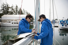 Sailing Teammates Fastening Sail To Boom