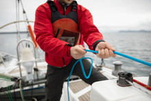 Man Adjusting Rigging Rope On Sailboat