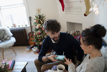 Boyfriend Giving Christmas Gift To Girlfriend In Living Room