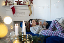 Young Woman With Headphones Relaxing, Watching Movie With Digital Tablet In Christmas Living Room