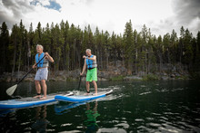 Mature Men Enjoying Standing Paddleboarding On Lake, Alberta, Canada