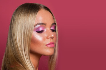 Young pretty model woman with makeup and blonde hair on pink background