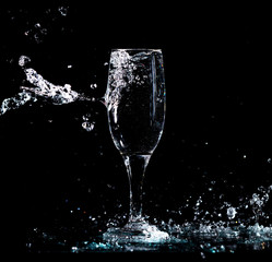 Wall Mural - Water with splashes in a glass on a black background