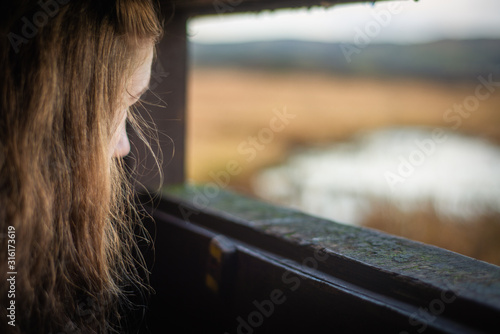 Fotografía A Young Woman Looks Out From a Bird Hide By A Scottish Loch