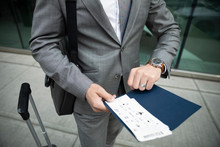 Businessman With Airplane Ticket Checking The Time On Wristwatch