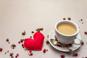 Good morning. Cup of coffee, rose buds and petals, red felt heart. Romantic breakfast, Valentine's Day. Stone concrete background