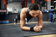© New Africa - Young woman doing plank exercise in modern gym