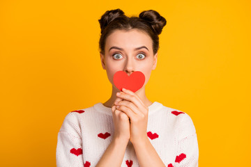 Wall Mural - Closeup photo of pretty funny lady hold little paper heart hiding mouth postcard shy person wear white red hearts pattern pullover isolated yellow color background