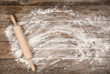 Flour and rolling pin on wooden table, flat lay