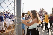 Girl Watching Baseball Game Behind Fence