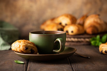 Green Cup Of Tea With Mini Chocolate Bun, Puff Pastry On Old Wooden Table. Tasty Tea Break Concept, Copy Space.