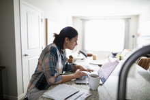 Woman Working From Home At Laptop In Kitchen